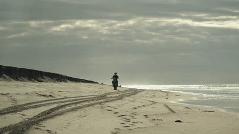 motociclista viaja en motocicleta de motocross en una playa de arena junto al mar brillante