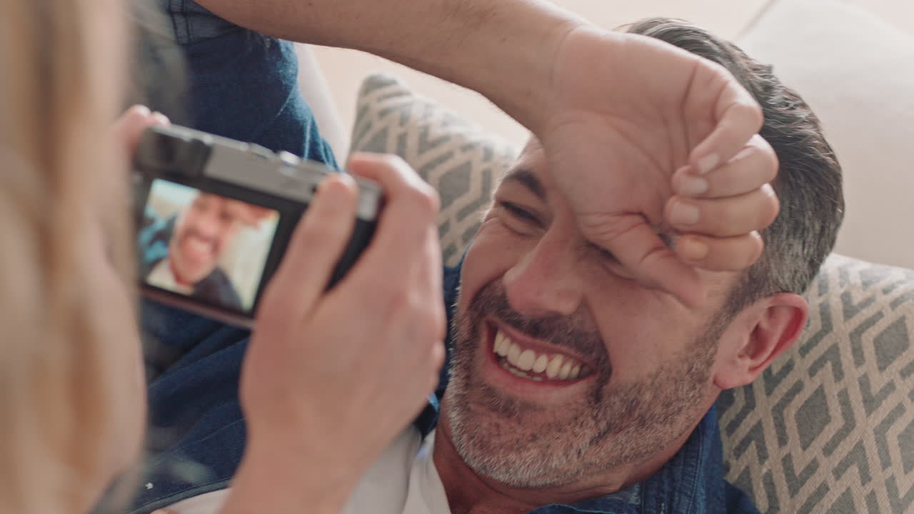 pareja feliz tomando fotos juntos usando la cámara divirtiéndose en casa en el sofá jugando disfrutando de una relación romántica