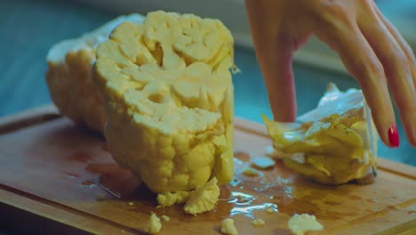 close up of female hands cutting in pieces white cauliflower with kitchens knife full frame