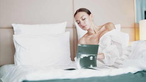 woman in elegant white dress reading in a hotel room