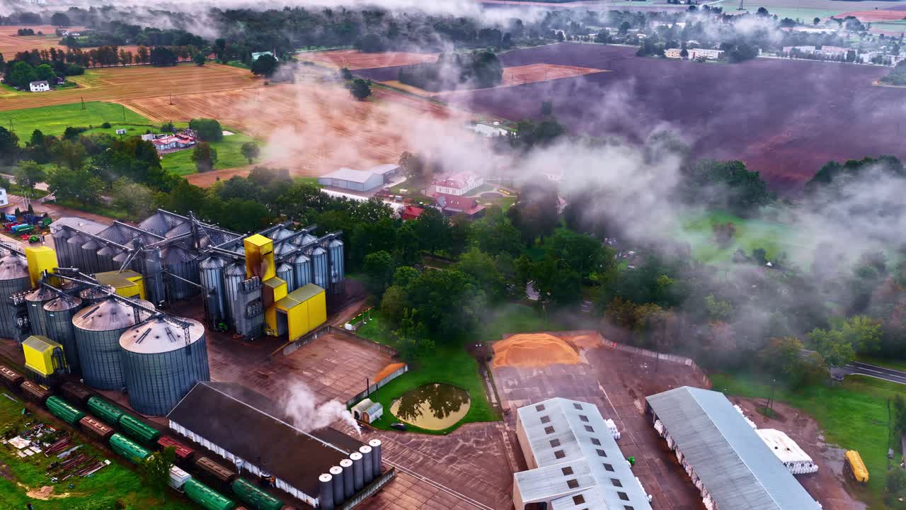 Aerial view of factory and countryside with misty fields, tranquil morning
