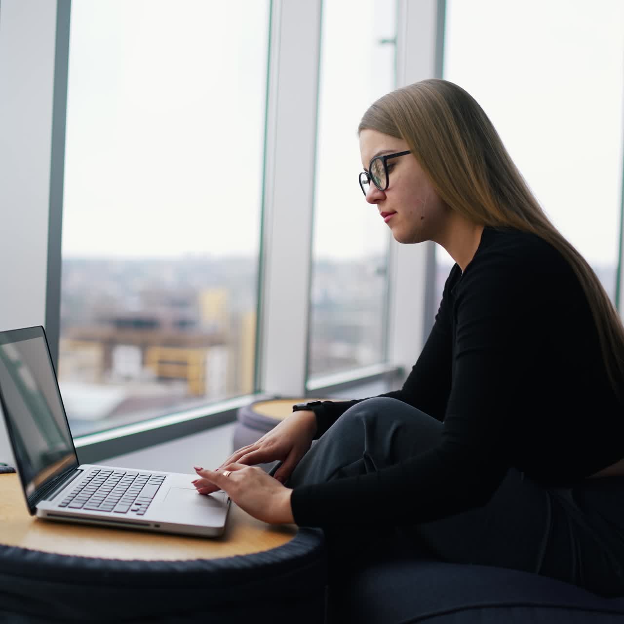 Giovane donna bella con gli occhiali che lavora al laptop.