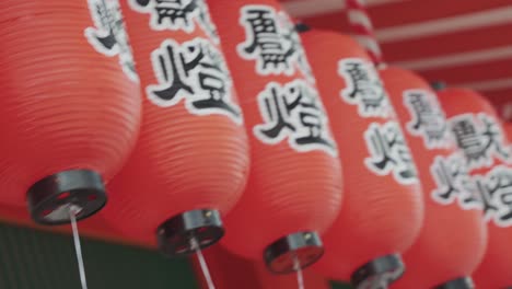 a close-up video capturing the intricate details of glowing red lanterns adorned with japanese writings at a temple, showcasing the spiritual ambiance and rich cultural heritage of the sacred site.
