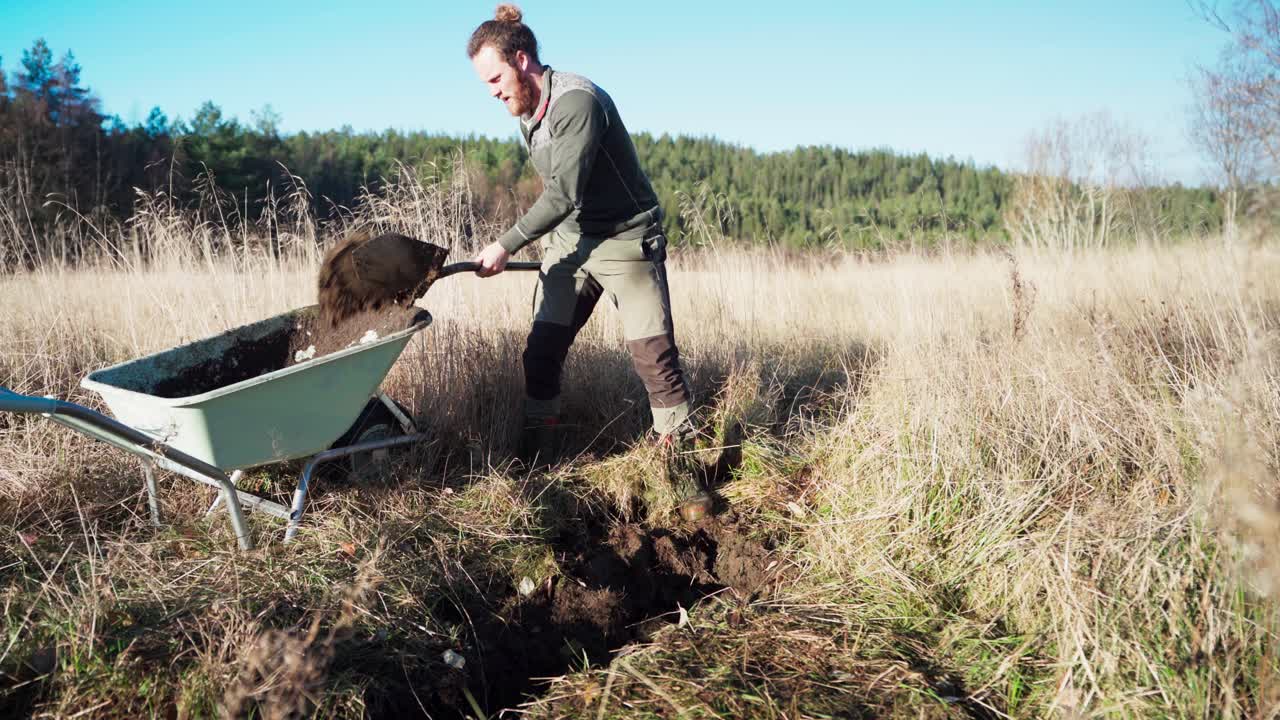 Caucasian Man Shoveling Soil And Placing In Wheel Barrow