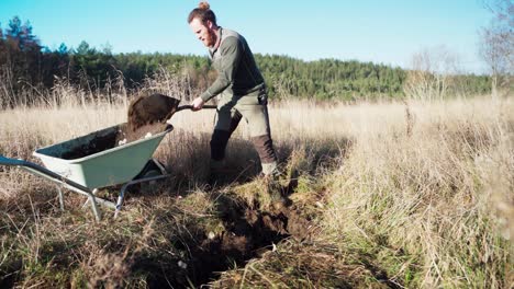 Caucasian-Man-Shoveling-Soil-And-Placing-In-Wheel-Barrow