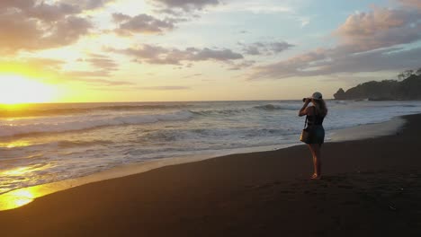 woman taking photos at beach during sunset in tropics