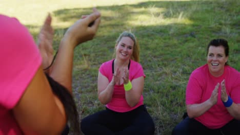 female trainer and women applauding trainee during obstacle course