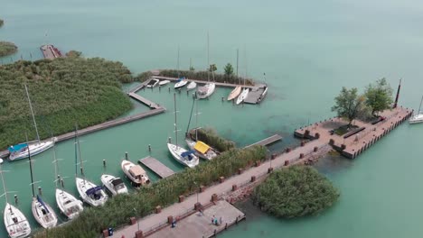 Pull-back-drone-shot-of-a-small-marina-in-a-vivid-blue-lake