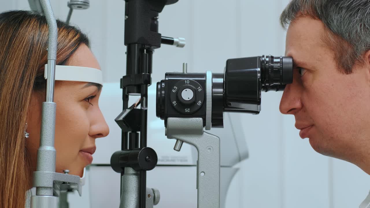 안과 의사 또는 안과 의사에서 굴절 측정기로 눈을 측정합니다. 안과 의사는 클리닉에서 젊은 여성의 안경 압력을 측정하고 있습니다.