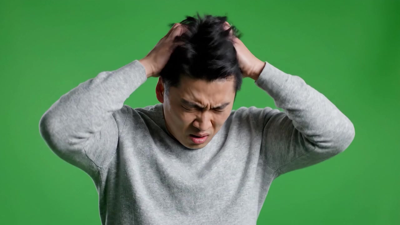 Capturing a Range of Emotions: A Man Expresses Frustration and Discomfort with a Green Background, Showcasing Body Language and Facial Expressions.
