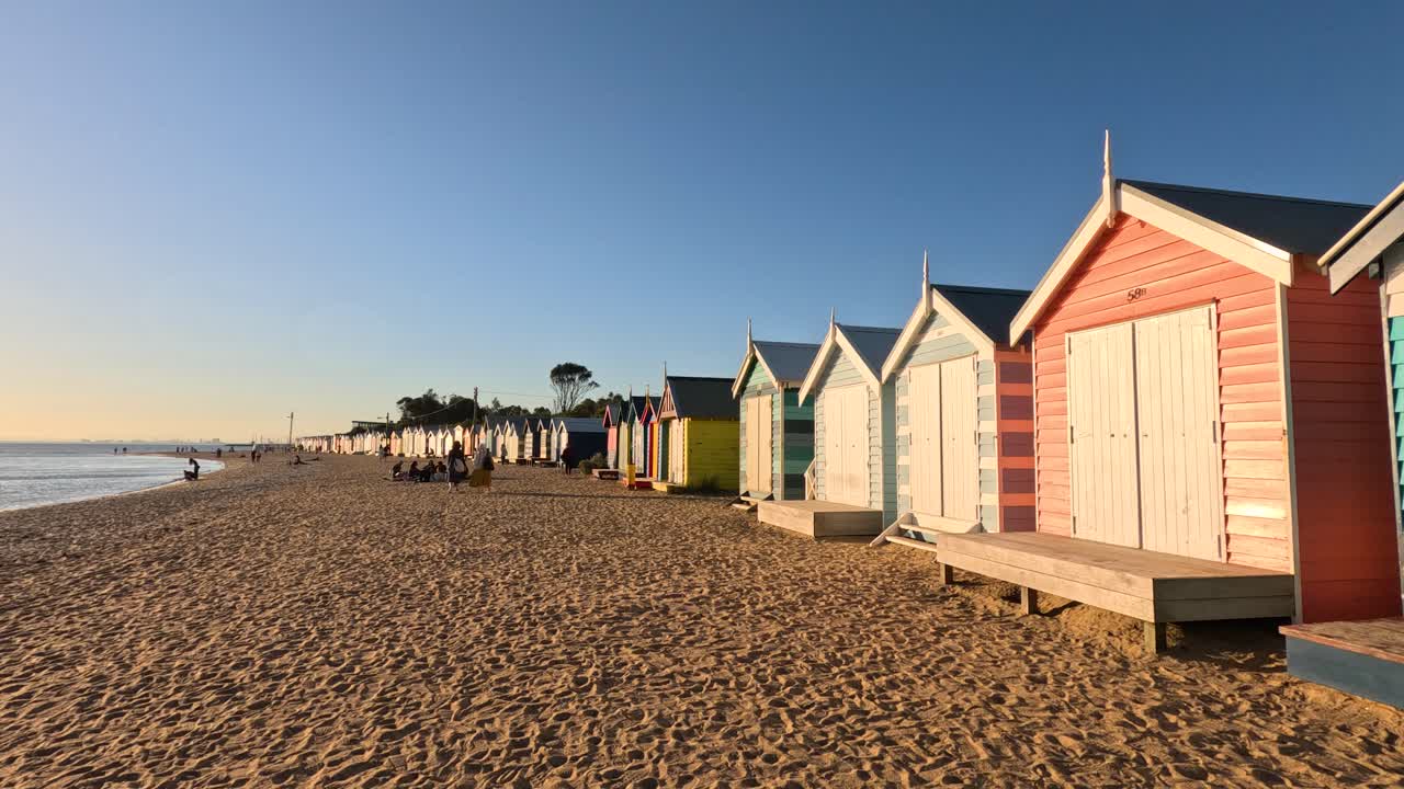 Farverige strandhytter med en nedgående sol