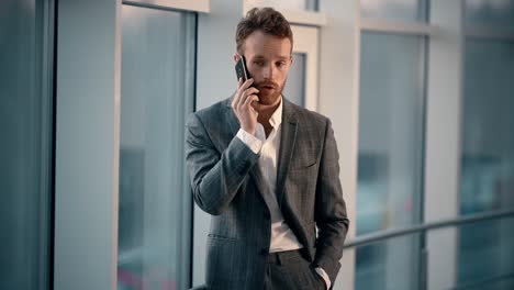 happy young man in business suit talking on the phone on the background of the night city in the office