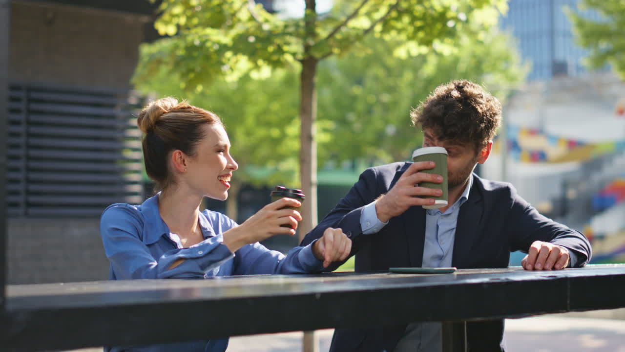 두 명의 노동자가 거리에서 커피를 마시고 있습니다. 즐거운 사업가들이 이야기하고 있습니다.
