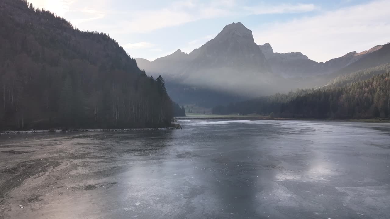 Calm frozen Obersee with mist and mountain backdrop in Näfels, Switzerland