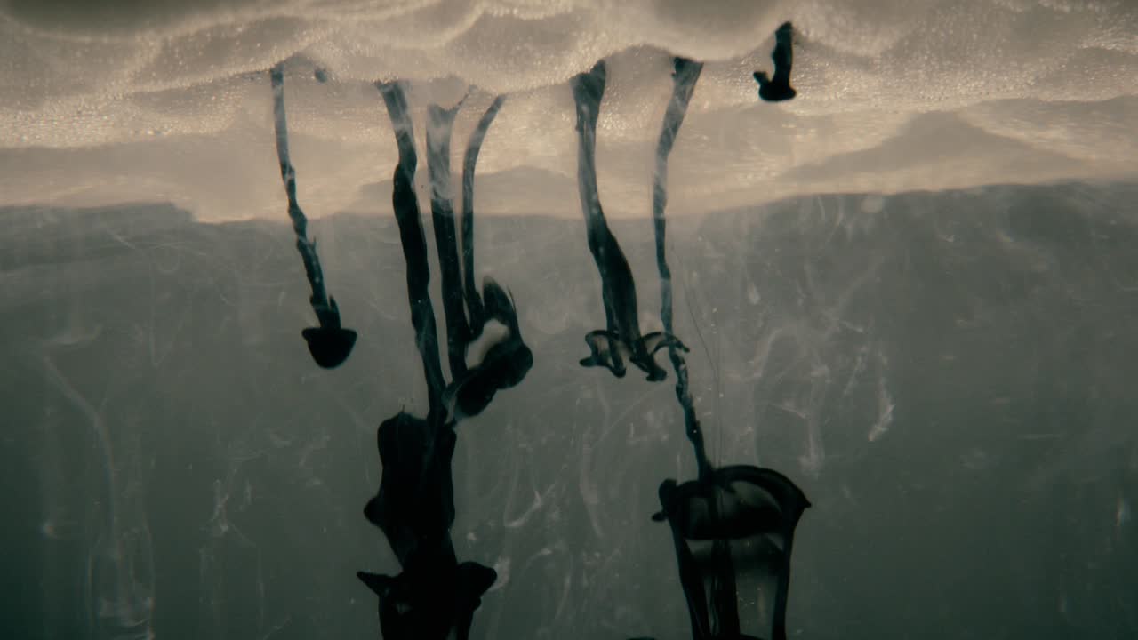 líquido de tinta negra cayendo en formas abstractas desde un cielo nublado