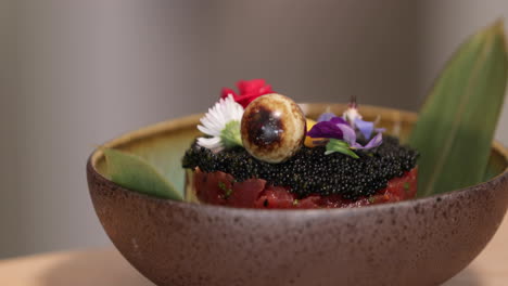 food plating - bowl of tuna tartare with black roe and fresh flowers