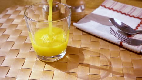 Orangensaft-In-Ein-Glas-Gießen,-Das-Morgendliche-Frühstück.-Zeitlupe-Mit-Rotierender-Kamerafahrt.