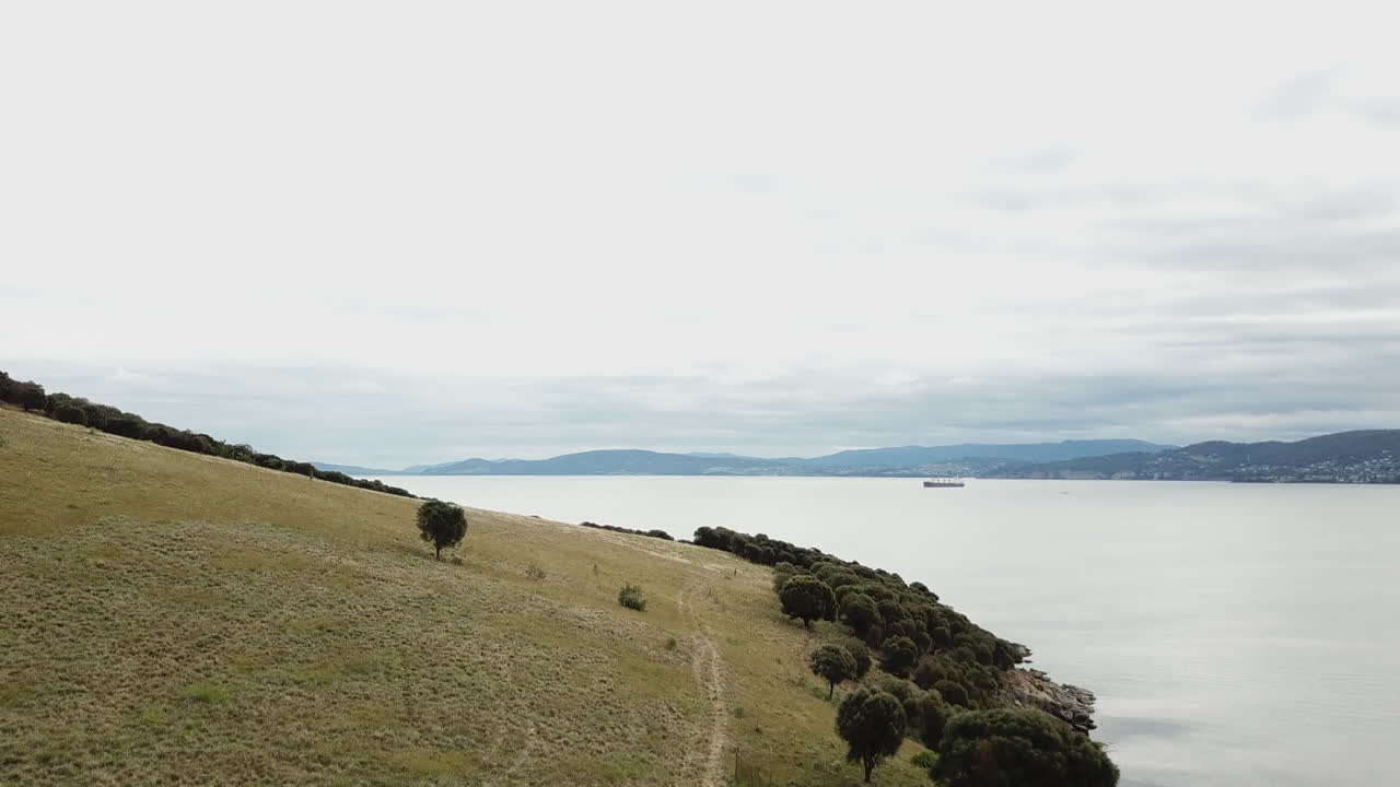 drone panorámica sobre la ladera revelando la plataforma petrolera en el fondo de australia
