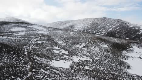 Aerial-drone-footage-panning-around-heather-moorland-in-the-Cairngorms-National-Park,-Scotland-in-Winter-looking-towards-Fiacaill-Coire-an-t-Sneachda-with-patchy-snow-and-rugged-mountain-scenery