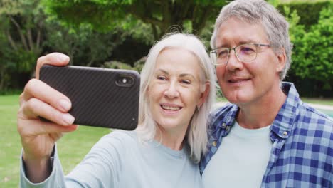 Animation-of-caucasian-senior-couple-embracing-in-garden,-taking-selfie