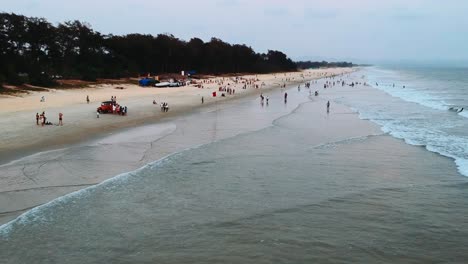 people at the beautiful beach in goa, india during summertime - aerial drone
