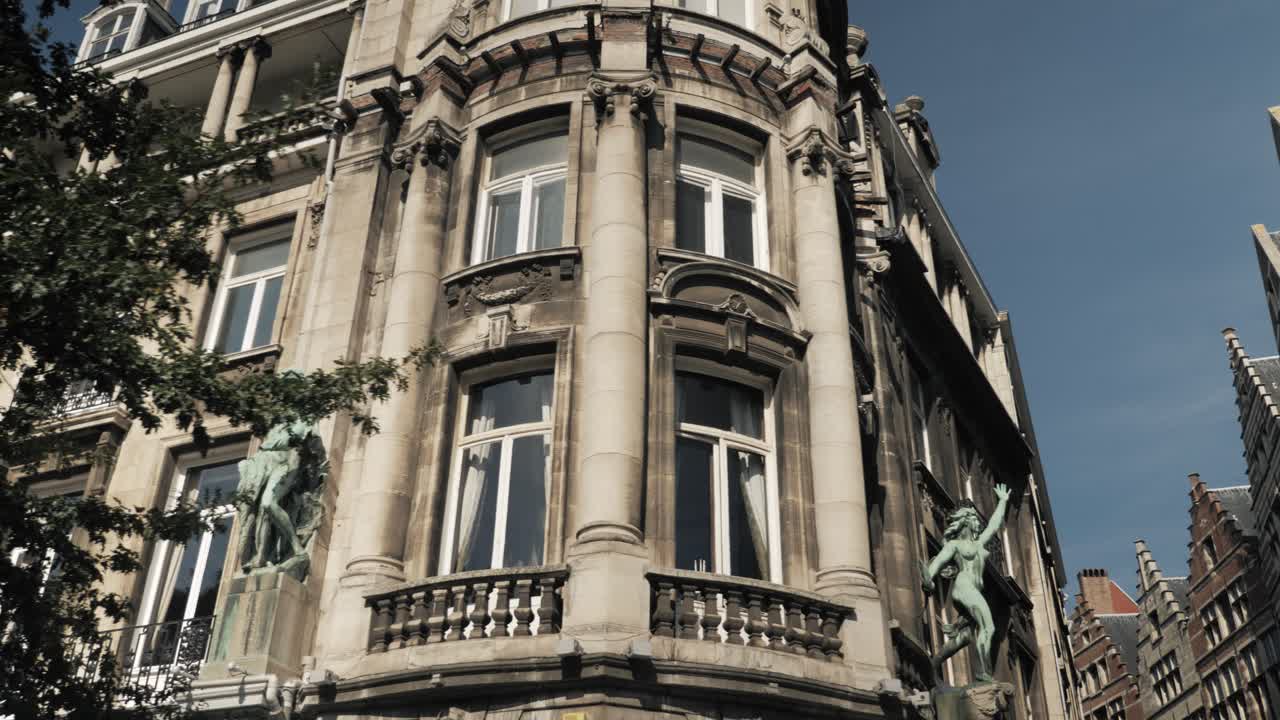 Historic Antwerp city architecture with intricate statues and detailed stone facades basking in sunlight against a crisp blue sky