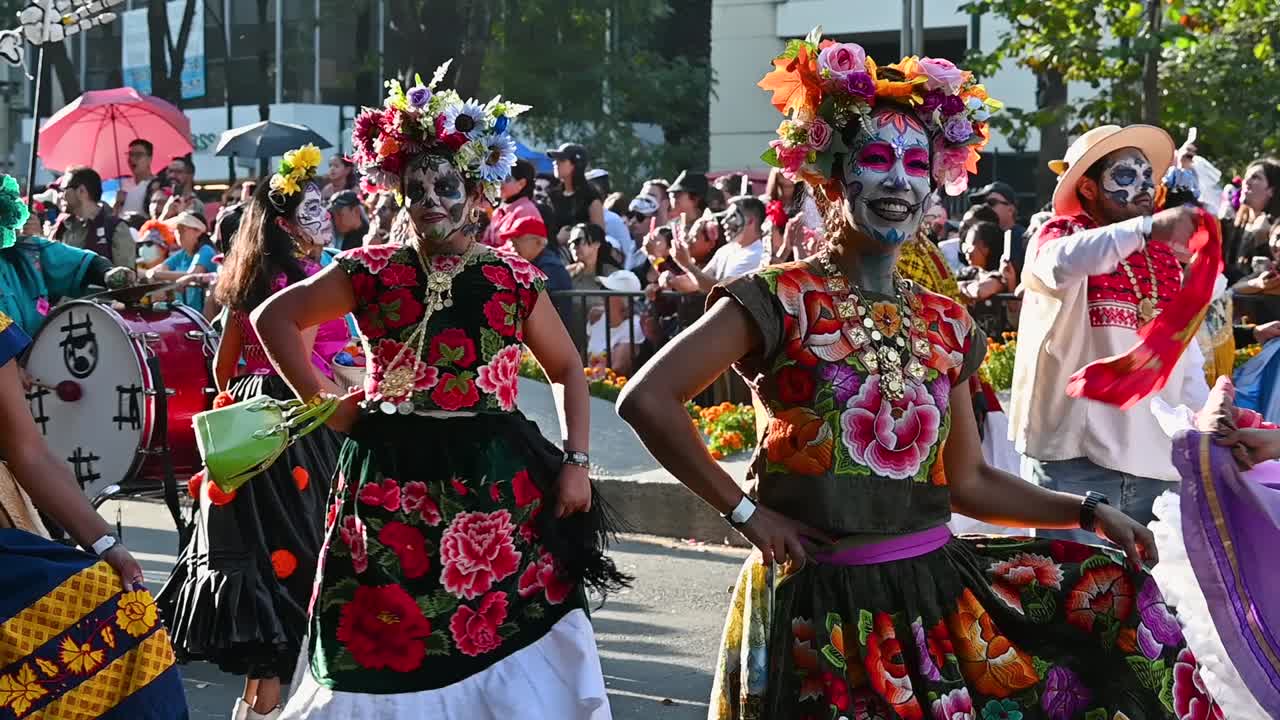 Mexican cultural heritage shines through traditional costumes at Day of the Dead parade, Performers in vibrant costumes swaying at Day of the Dead parade