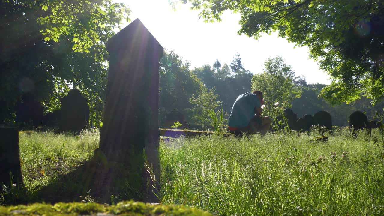 태양 아래 묘지에서 울고 있는 남자