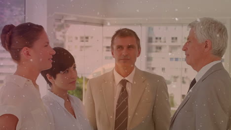 partículas blancas flotando contra diversos hombres de negocios discutiendo juntos en la oficina