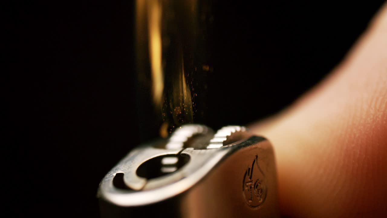 maravillarse del movimiento gracioso de un pulgar encendiendo un encendedor, chispas en cascada en llamas en hipnotizante cámara lenta