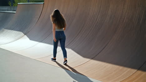 young woman walking alone in an empty skate park half-pipe