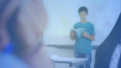 Ecuaciones-Matemáticas-Flotando-Contra-Un-Niño-Caucásico-Leyendo-Un-Libro-En-Clase-En-La-Escuela-Primaria