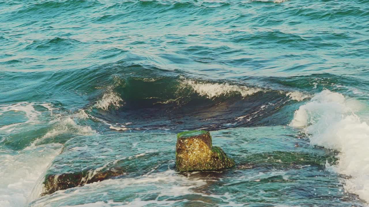 Breakwater and splashes of wave in sea shore. Slow motion