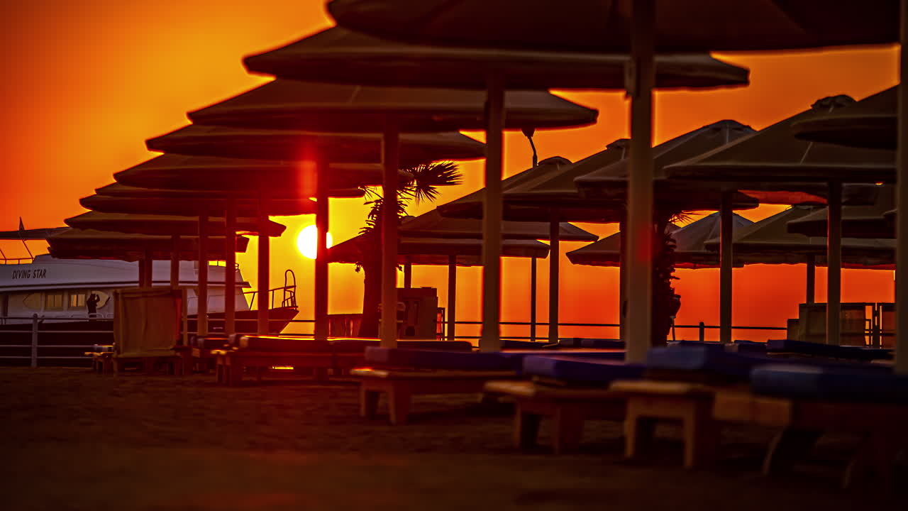 이집트 홍해의 해변 파라솔 너머에 정박한 요트와 함께 일출 시간 경과