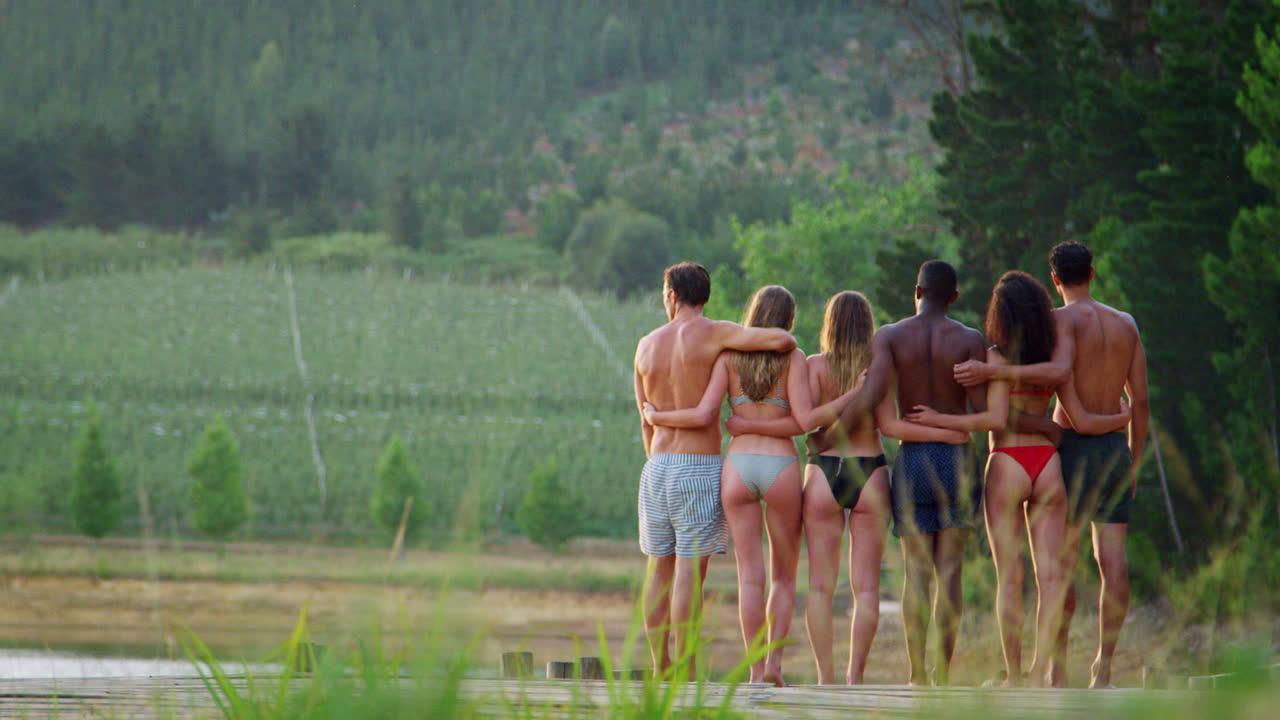 Adult friends on jetty, back view right of frame, closer up