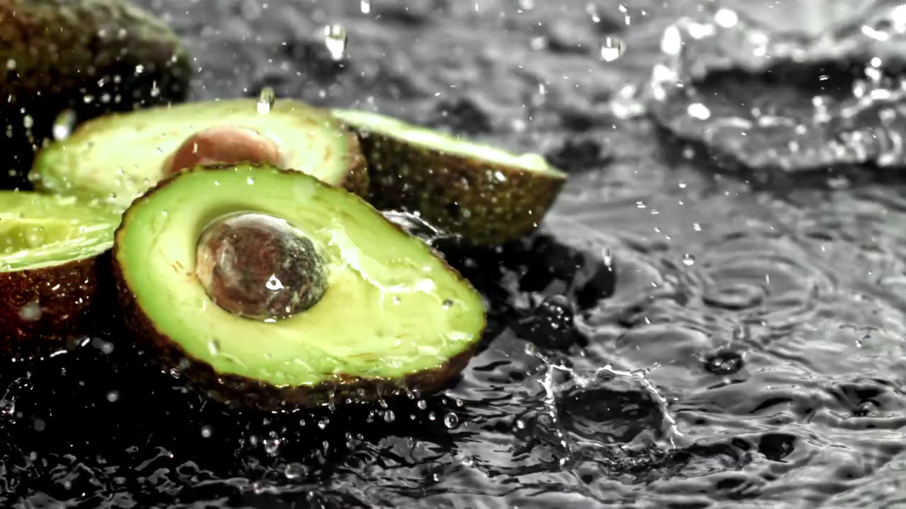 Gocce d'acqua al rallentatore che schizzano su avocadi appena tagliati