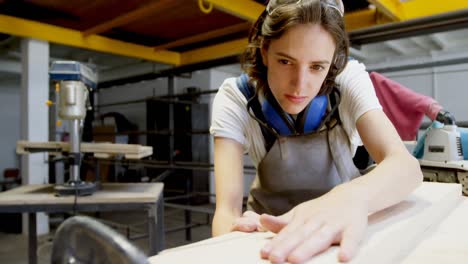 female welder examining a wooden plank 4k