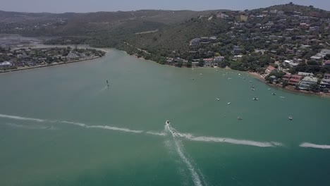 windsurfer and motorboat return to shore in shallow green lagoon