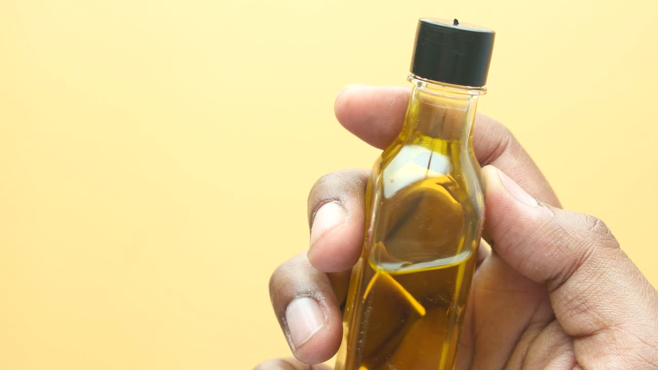 persona sosteniendo una pequeña botella de aceite amarillo