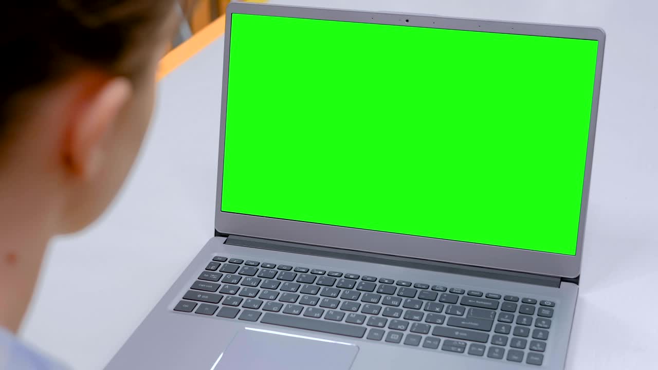 mujer mirando una computadora portátil con una pantalla verde en blanco en un café