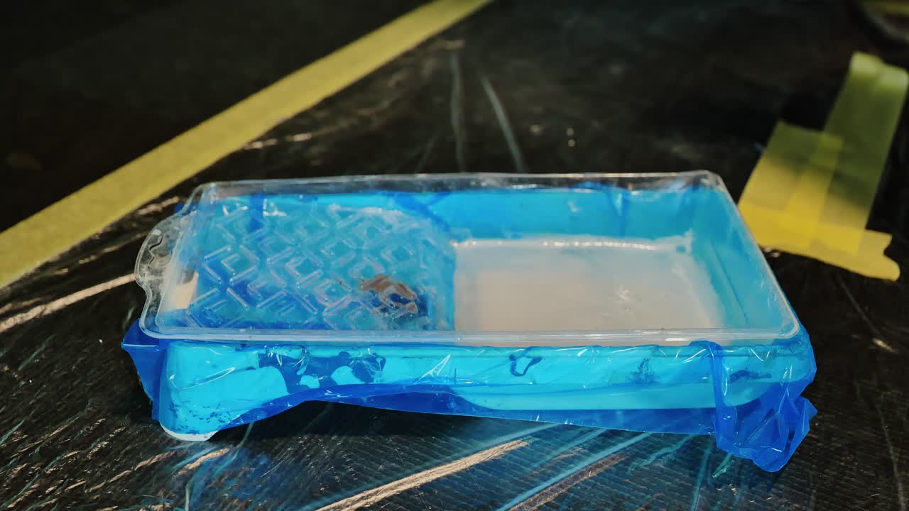 Worker dips roller in primer to prepare surfaces before wall coating begins