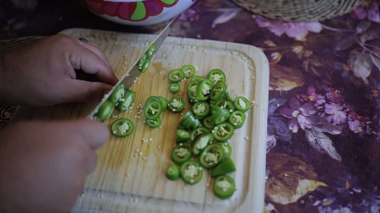 Vista de cima: Fatiando pimentas jalapeño em uma tábua de corte de madeira