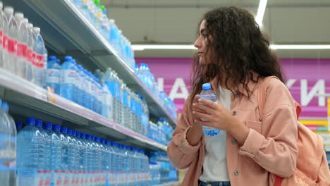mujer comprando botellas de agua en un supermercado
