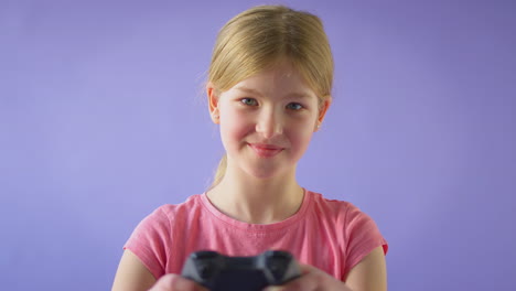 studio shot of girl gaming with controller against purple background