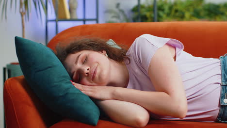 tired young woman girl lying down in bed taking a rest at home, napping, falling asleep on couch