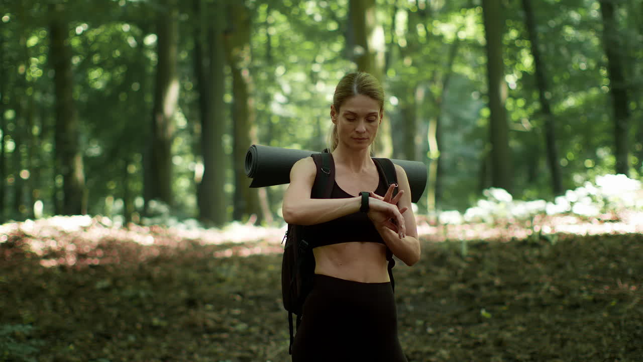 Woman checking smartwatch during a hike in the forest