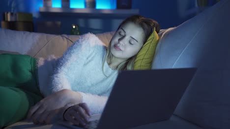 sleepy and exhausted young woman looking at laptop.