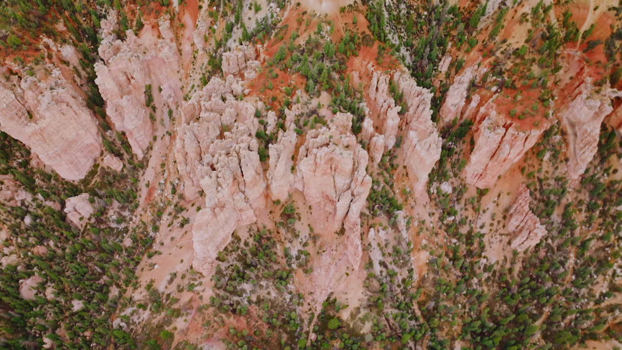 Slow descending over the tremendous rocks of Bryce Canyons in Utah, United States. Little pine trees grooving on the slopes of wonderful landscape. Top view.