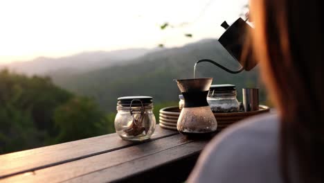 a woman making drip coffee with a beautiful nature view in the morning