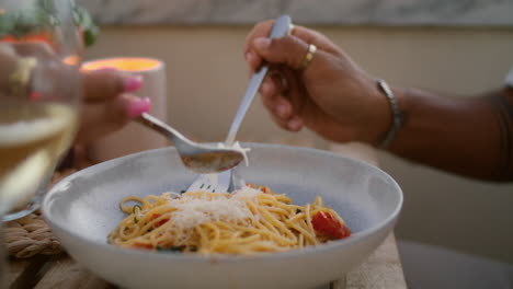 unknown man eating spaghetti vertically closeup. woman hands decorating food